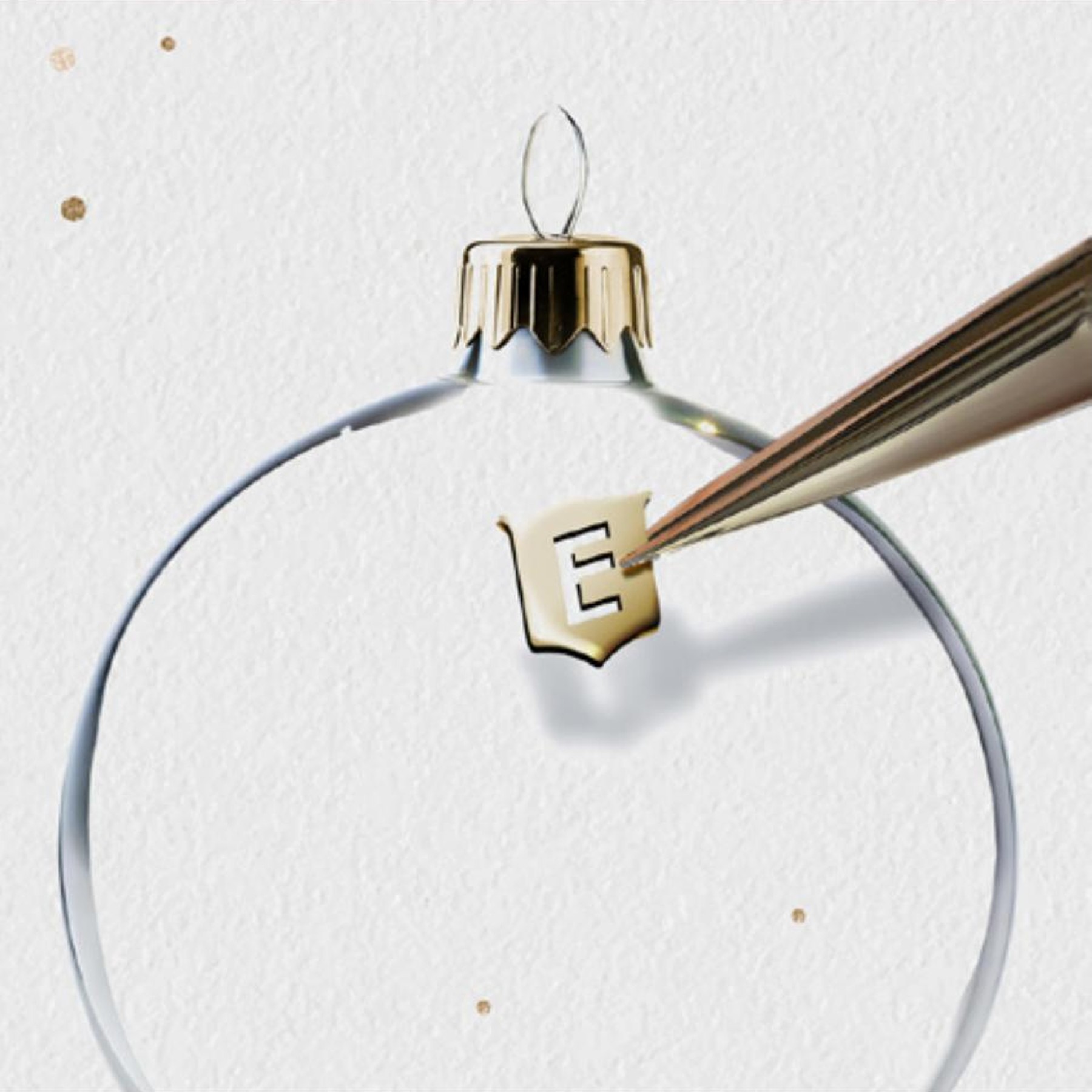 Concept Season's Greetings Eberhard & Co., dettaglio del logo E applicato sulla sommità di una pallina di Natale, sfondo chiaro